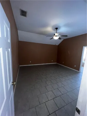 en empty room with a chandelier fan and window