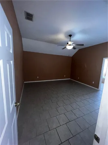 en empty room with a chandelier fan and window