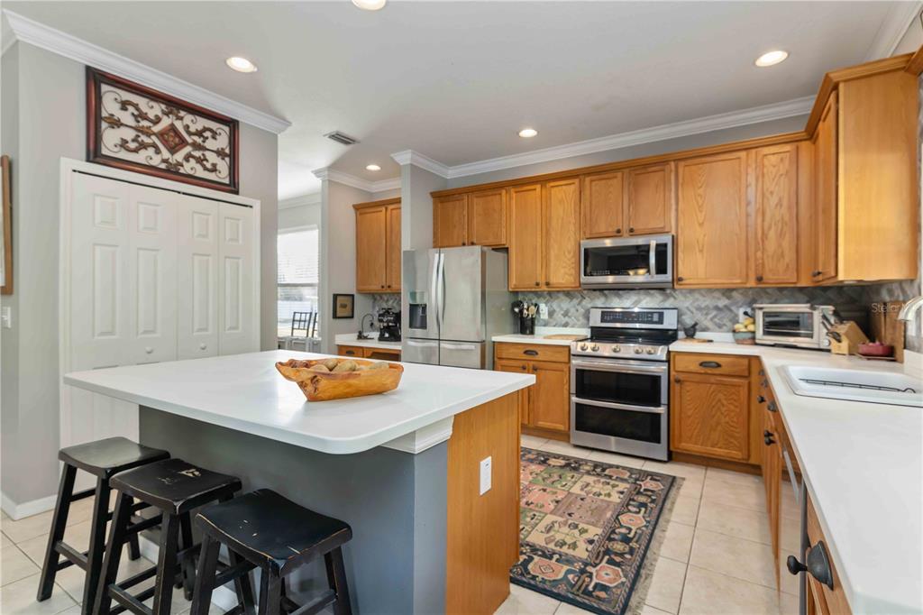 3907 62nd Terrace East Bradenton, FL 34203 - Photo 12 of 63 a kitchen with stainless steel appliances a stove a sink a microwave a refrigerator and white cabinets with wooden floor