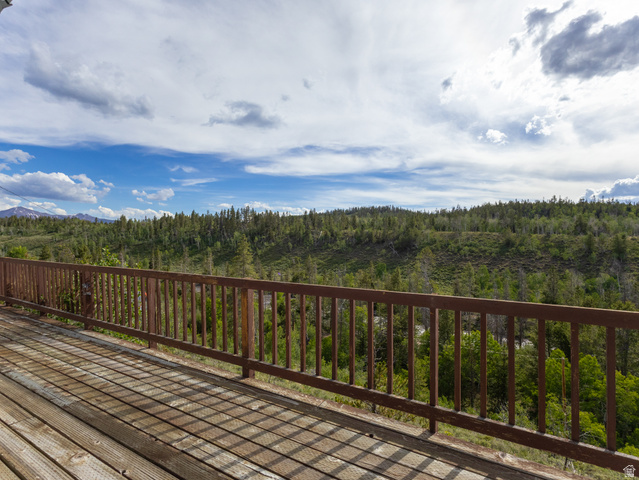 4770 Pine Crest Road Evanston, UT 82930 - Photo 5 of 24 Expansive wood deck with a durable railing system, surrounded by a natural landscape of mature trees and distant mountains