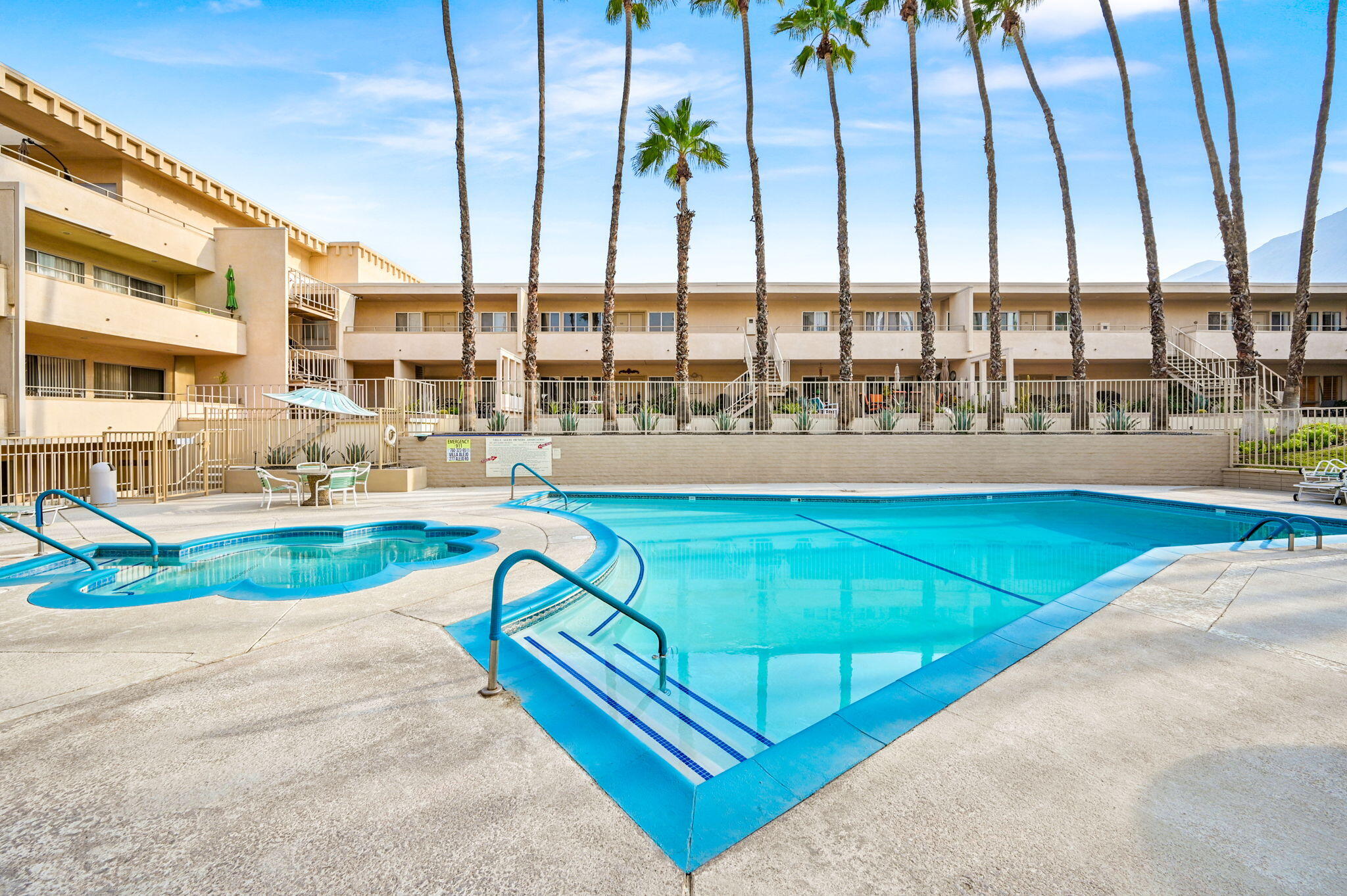 277 East Alejo Road, Unit 215 Palm Springs, CA 92262 - Photo 19 of 52 a view of a swimming pool with a lawn chairs under an umbrella