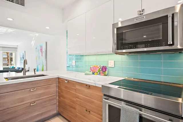 a large white kitchen with a large counter top and stainless steel appliances