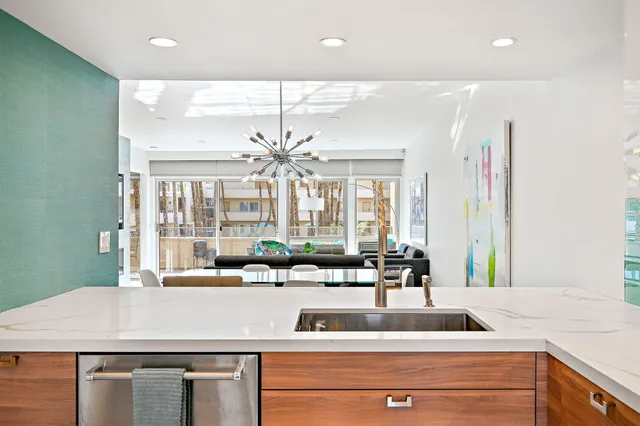 a living room with stainless steel appliances furniture a rug and a kitchen