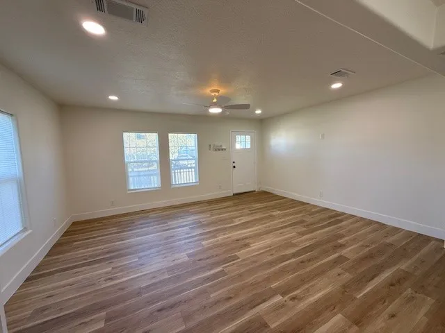 an empty room with wooden floor and windows