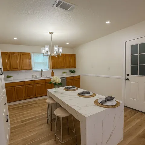 a kitchen with a sink a stove cabinets and wooden floor