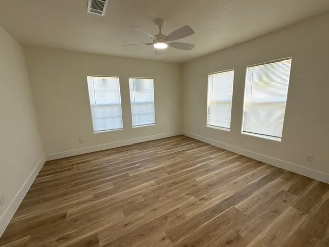 an empty room with wooden floor and windows