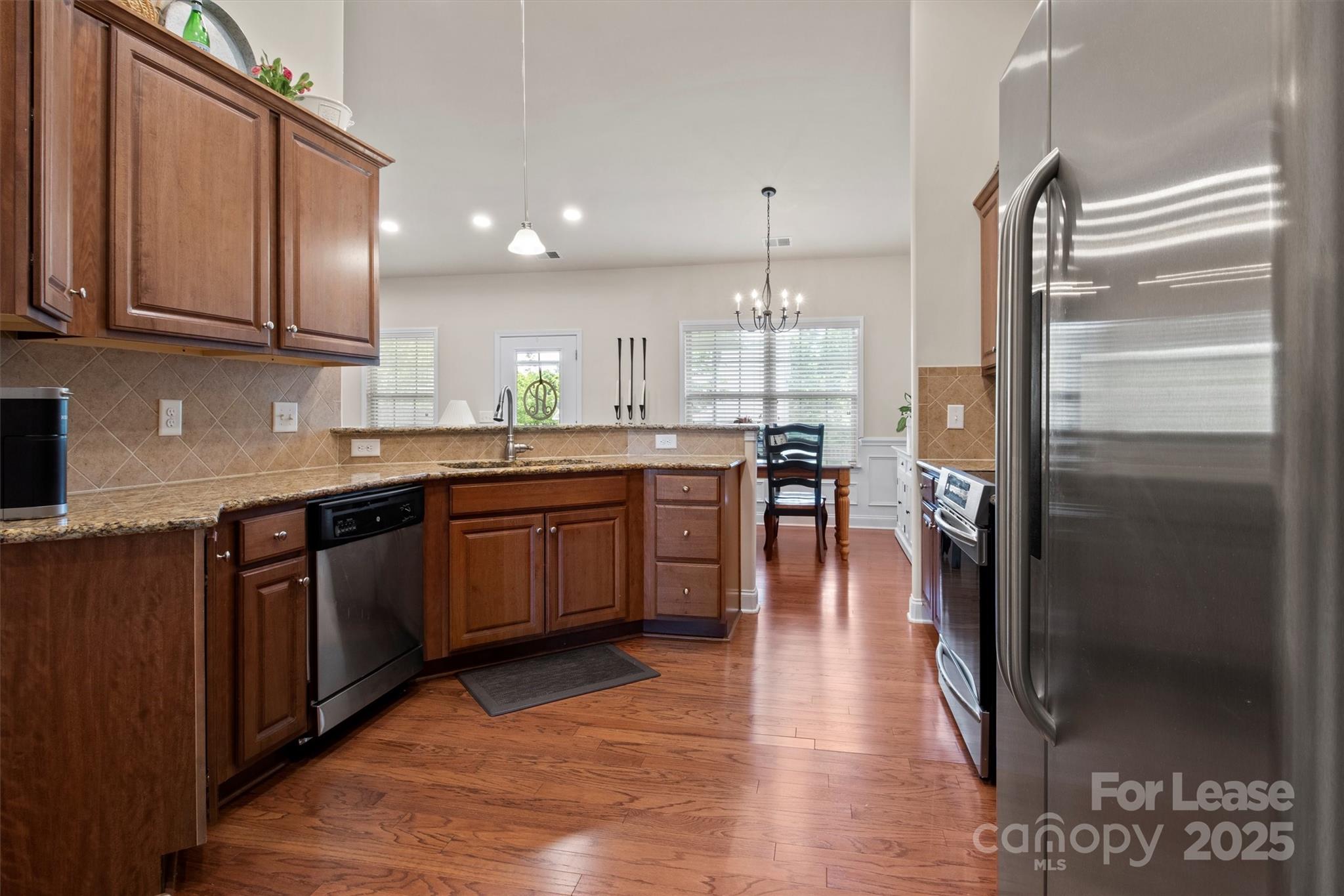7266 Kenyon Drive Denver, NC 28037 - Photo 10 of 25 a kitchen with stainless steel appliances granite countertop a refrigerator a sink dishwasher a stove and white countertops with wooden floor
