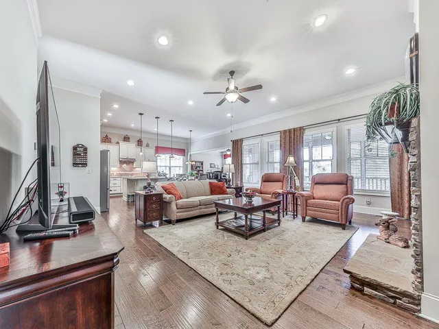 a living room with furniture kitchen view and a wooden floor