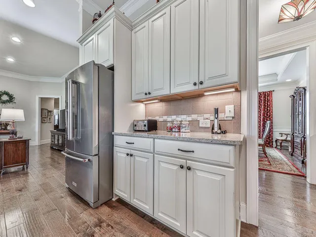 a large white kitchen with a white countertops a sink and a stove with wooden floor