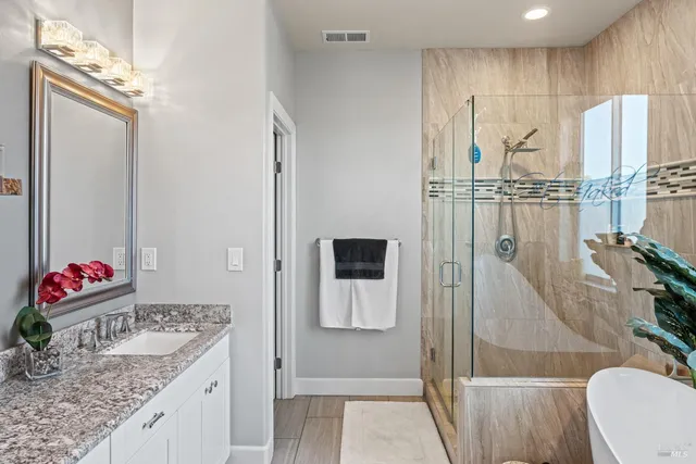 a bathroom with a granite countertop sink a mirror and shower