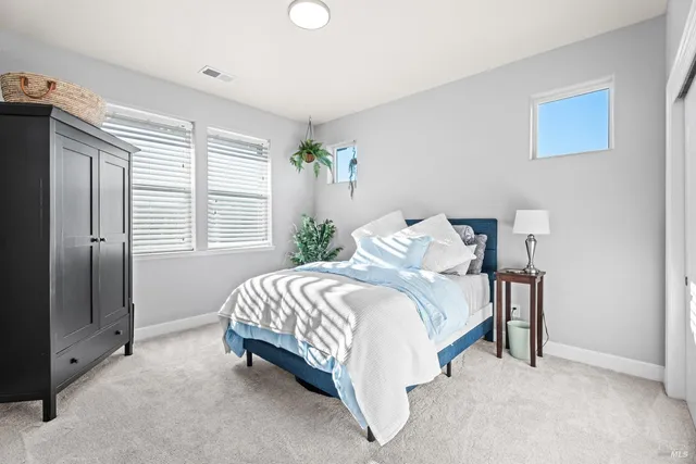 a bed sitting in a bedroom next to a window and a larger closet