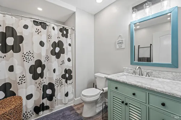 a bathroom with a granite countertop toilet a sink a mirror a shower curtain and a large mirror