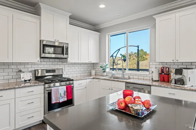 a kitchen with kitchen island granite countertop a stove a sink dishwasher and cabinets with wooden floor