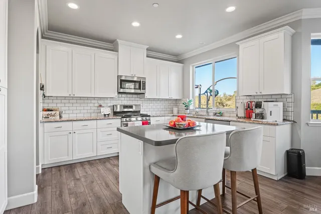 a kitchen with stainless steel appliances granite countertop a white cabinets and wooden floor