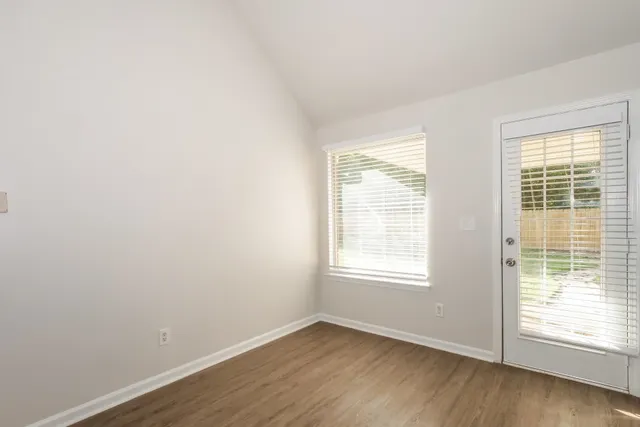 an empty room with wooden floor and windows