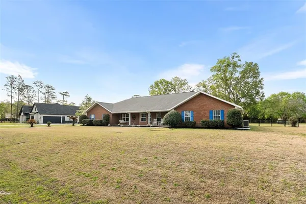 a view of a house with a yard and large trees