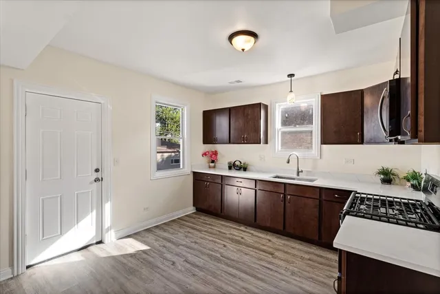 a kitchen with stainless steel appliances a sink stove and wooden floor