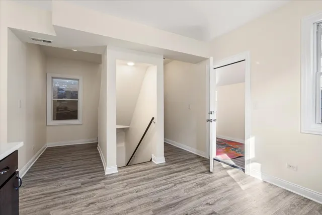 a view of an empty room with wooden floor and a bathroom
