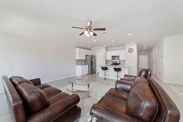 a living room with furniture kitchen view and a chandelier