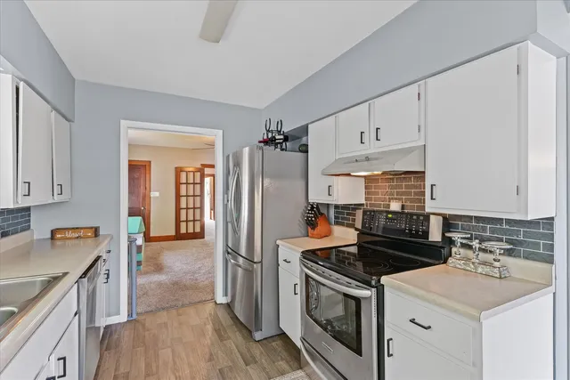 a kitchen with white cabinets and appliances