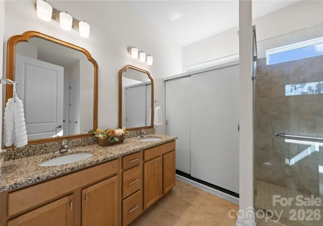 a bathroom with a granite countertop double vanity sink and a mirror