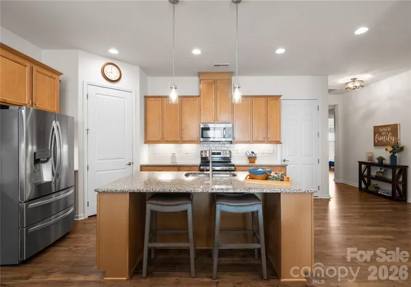 a kitchen with stainless steel appliances granite countertop a table chairs sink refrigerator and microwave