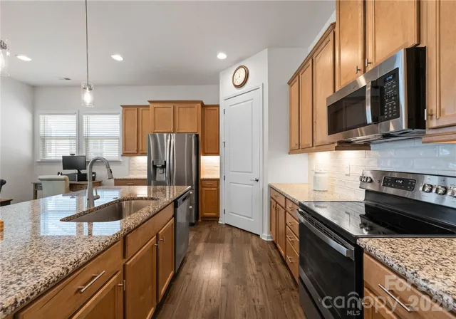 a kitchen with stainless steel appliances granite countertop a sink stove and refrigerator