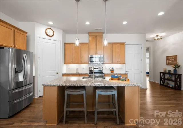 a kitchen with stainless steel appliances granite countertop a table chairs sink refrigerator and microwave