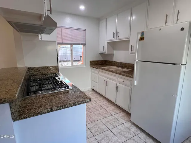 a kitchen with granite countertop a refrigerator stove top oven and sink