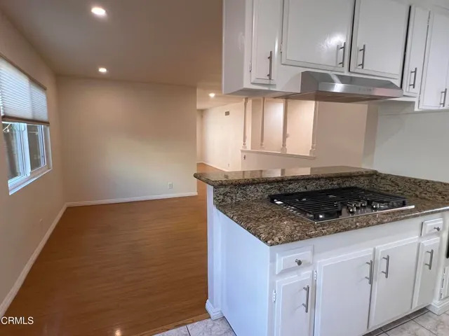 a kitchen with granite countertop stainless steel appliances a sink stove and cabinets