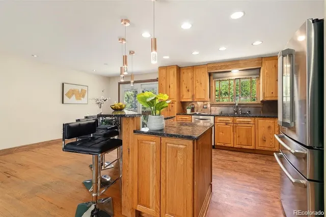 a kitchen with stainless steel appliances kitchen island granite countertop a sink and a refrigerator