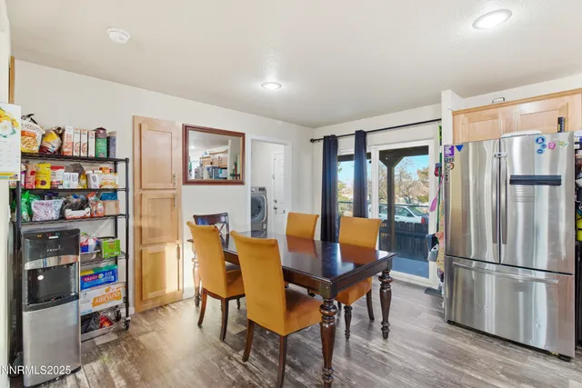 a dining room with stainless steel appliances a refrigerator and a dining table with wooden floor