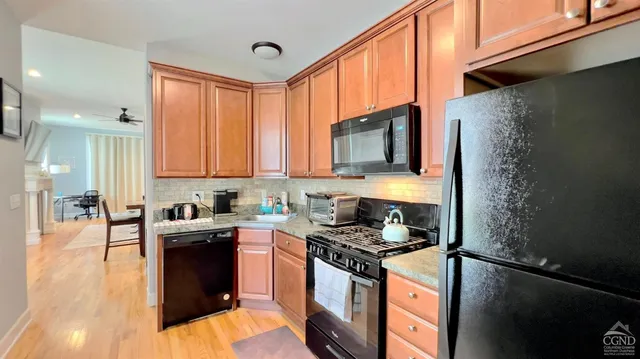 a kitchen with stainless steel appliances granite countertop a stove a sink dishwasher and a refrigerator with wooden floor