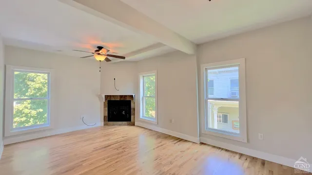 an empty room with windows and chandelier fan