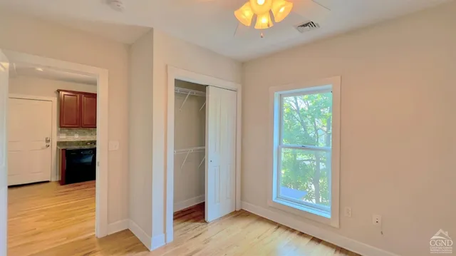 an empty room with wooden floor closet and windows
