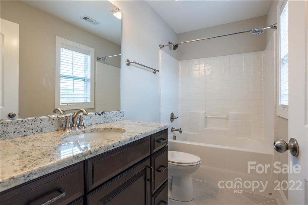 907 Ospre Lane Fort Mill, SC 29708 - Photo 22 of 39 a bathroom with a granite countertop sink toilet a large mirror a bathtub and shower