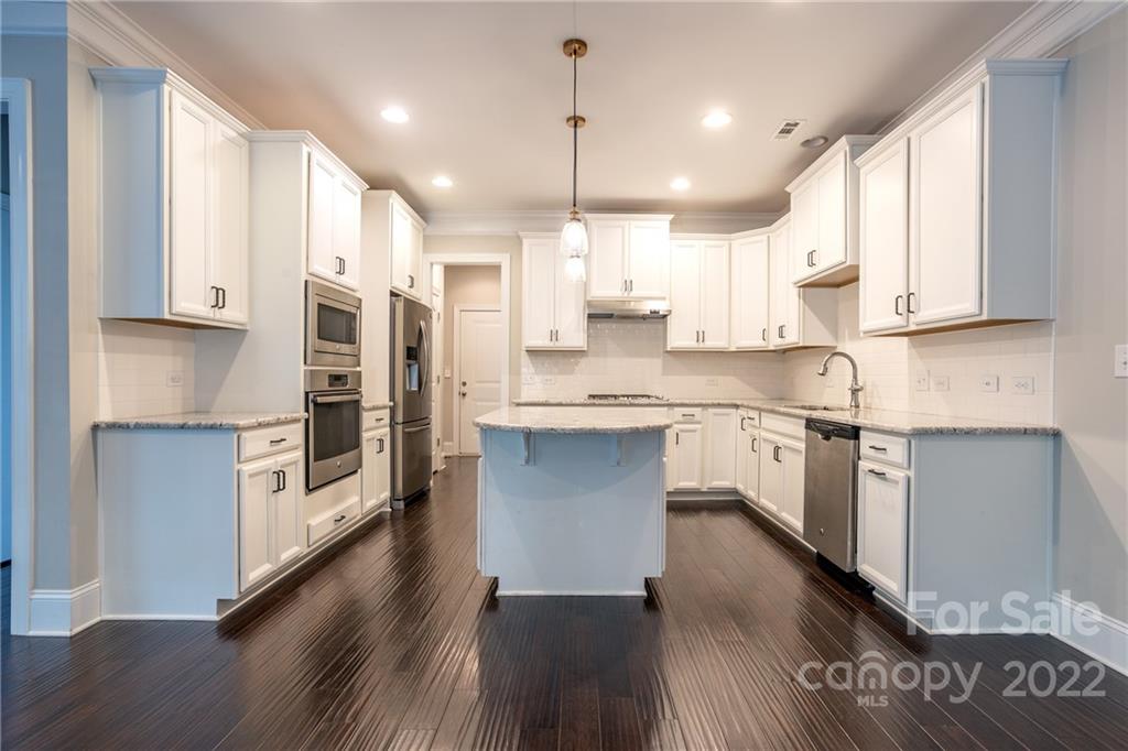 907 Ospre Lane Fort Mill, SC 29708 - Photo 9 of 39 a kitchen with stainless steel appliances granite countertop a refrigerator a sink dishwasher a stove and white cabinets with wooden floor