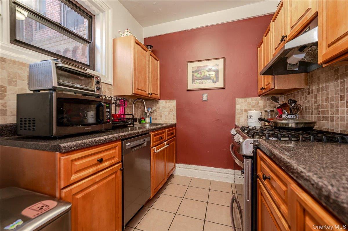 83-00 Talbot Street, Unit 2B Queens, NY 11415 - Photo 11 of 16 a kitchen with stainless steel appliances granite countertop a stove and a microwave