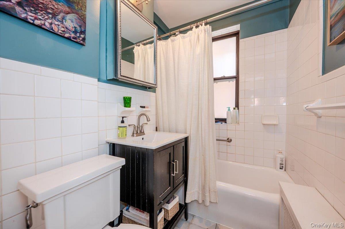 83-00 Talbot Street, Unit 2B Queens, NY 11415 - Photo 14 of 16 a bathroom with a sink a bath tub and a shower