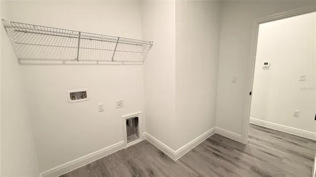 an empty room with wooden floor and fan