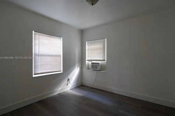 an empty room with wooden floor cabinet and windows