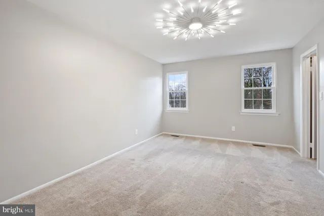 an empty room with windows and chandelier fan