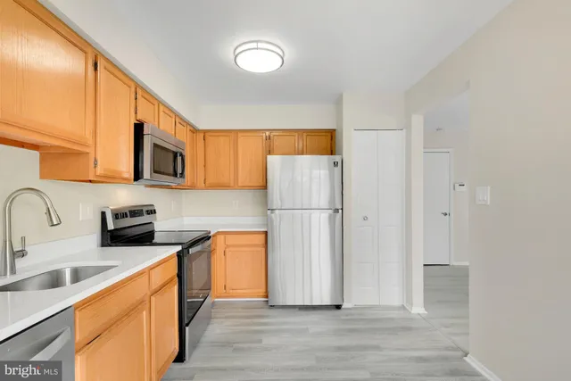 a kitchen with stainless steel appliances granite countertop a refrigerator a sink dishwasher a stove with wooden cabinets and floors