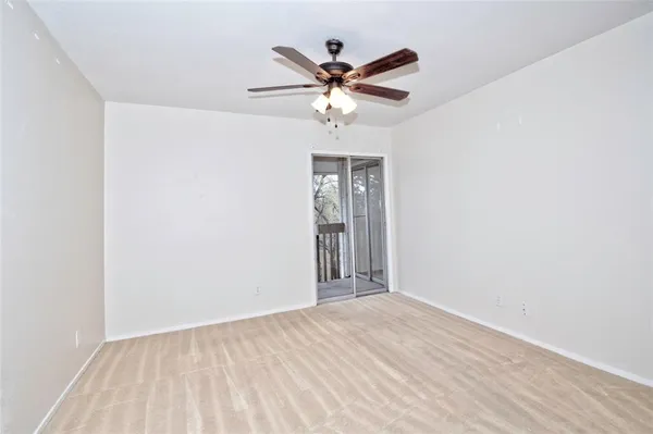 an empty room with ceiling fan and window