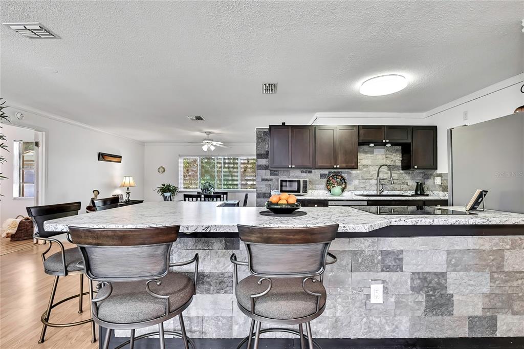 9059 Gaynor Street Spring Hill, FL 34608 - Photo 12 of 36 a kitchen with sink a stove and chairs with kitchen island