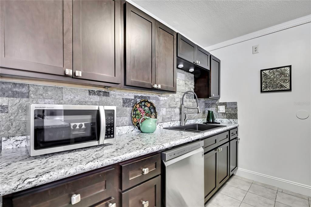 9059 Gaynor Street Spring Hill, FL 34608 - Photo 16 of 36 a kitchen with granite countertop stainless steel appliances a sink stove and microwave