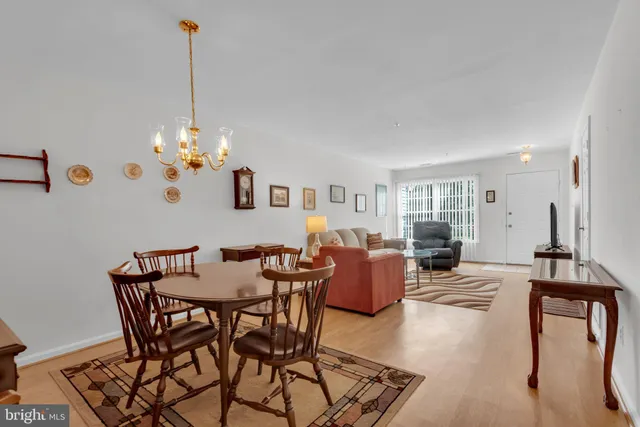 a view of a livingroom and dining room with furniture wooden floor a chandelier
