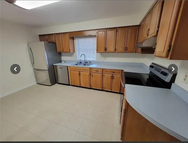 a kitchen with stainless steel appliances a refrigerator a sink a stove top oven a counter space and cabinets