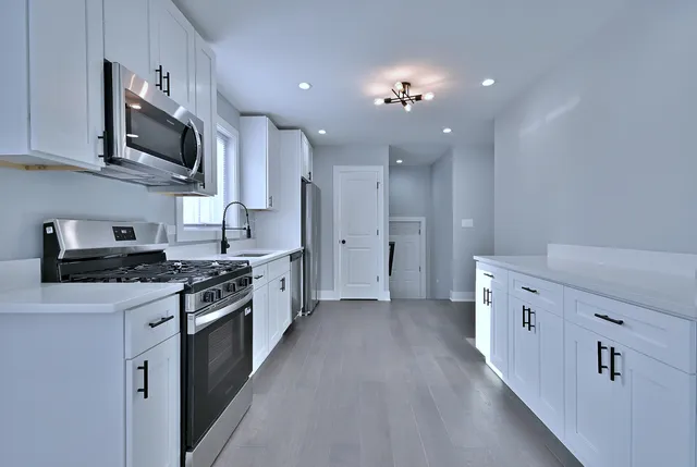 a large kitchen with stainless steel appliances granite countertop a lot of cabinets a stove and a refrigerator