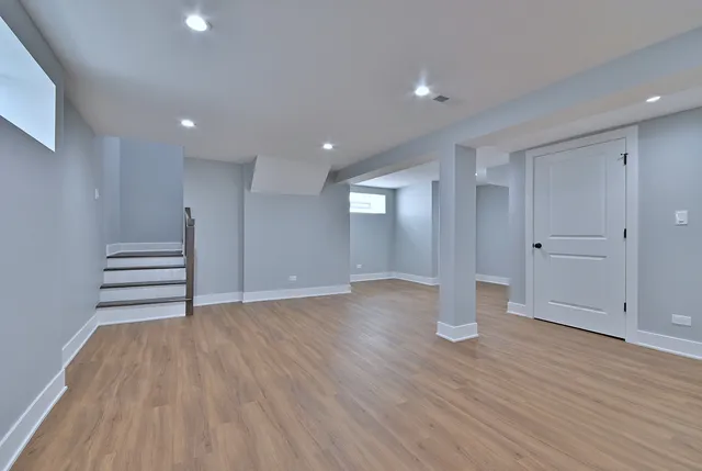 a view of an empty room with wooden floor and window